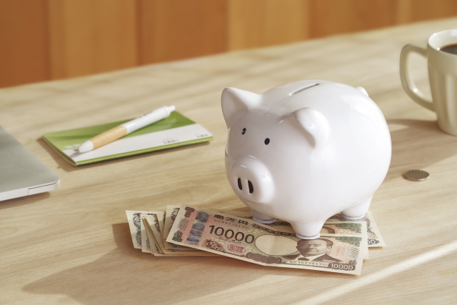 Vポイントを貯めることで得られる節約効果。一万円札と豚の貯金箱が並んだ、家計の貯蓄やポイント活用を連想させる風景。