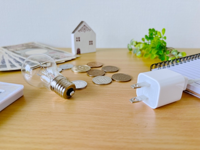 電気の使用と家計の関係を示すイメージ。コンセント、電球、現金を並べ、オクトパスエナジーによる電気代節約の効果を表現。